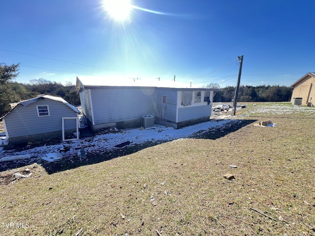 rear view of house featuring central AC unit and a lawn