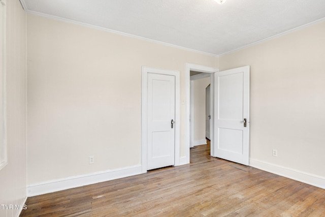 empty room with light wood-type flooring, baseboards, and ornamental molding