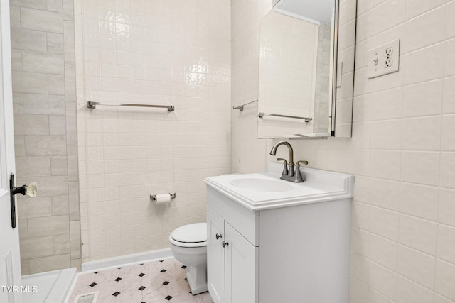 full bath with toilet, vanity, and tile walls