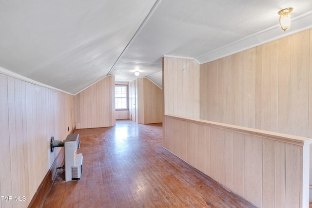 bonus room with lofted ceiling, light wood finished floors, and wood walls