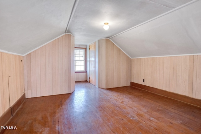 bonus room with lofted ceiling, wood walls, and wood finished floors