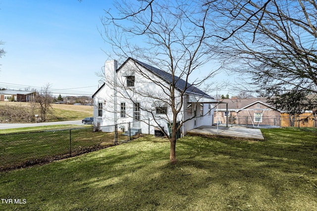 view of home's exterior with a patio, a yard, a chimney, and fence