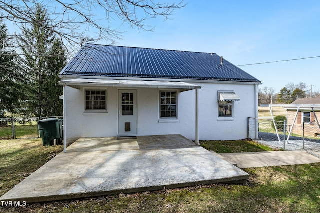 back of property with stucco siding, fence, metal roof, and a patio