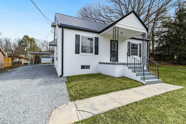 view of front facade with stucco siding, a front yard, a standing seam roof, metal roof, and a carport