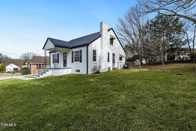 view of side of home featuring a yard, metal roof, fence, and a chimney