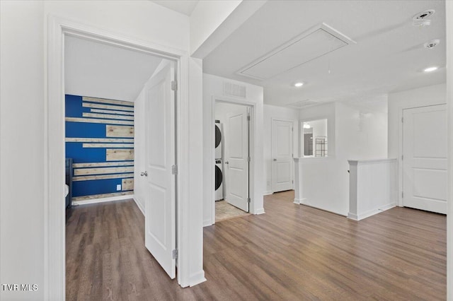 interior space with attic access, baseboards, visible vents, stacked washer and clothes dryer, and wood finished floors