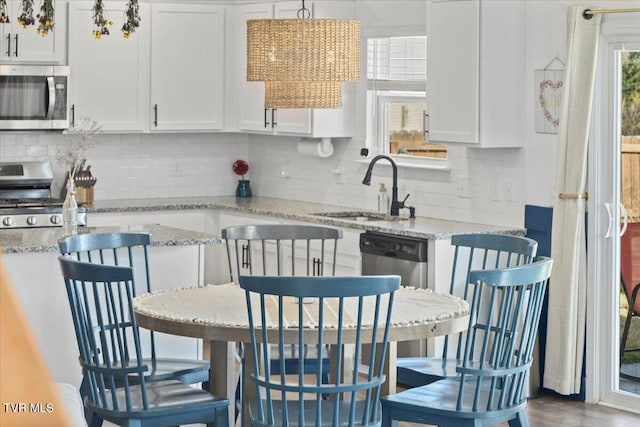 kitchen with stainless steel appliances, white cabinetry, and a sink