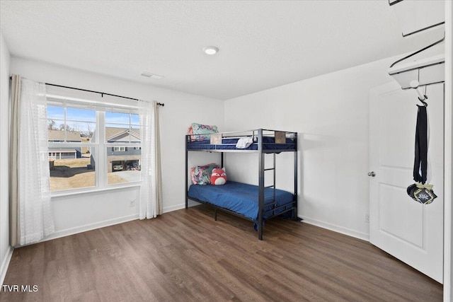 bedroom with visible vents, baseboards, dark wood finished floors, and a textured ceiling