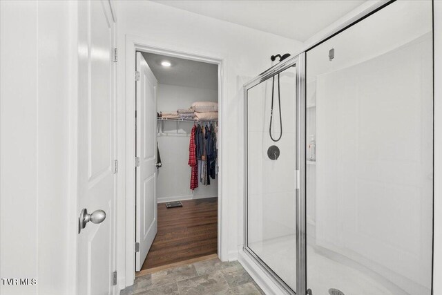 full bathroom with a stall shower and a spacious closet