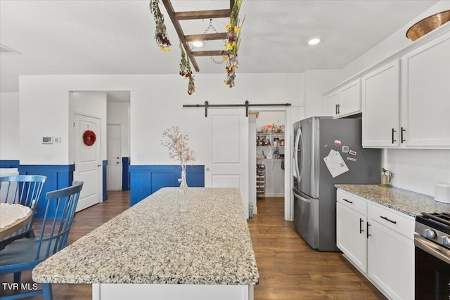 kitchen with light stone countertops, white cabinets, a kitchen island, and a barn door