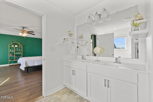 ensuite bathroom featuring ensuite bathroom, double vanity, a sink, and baseboards