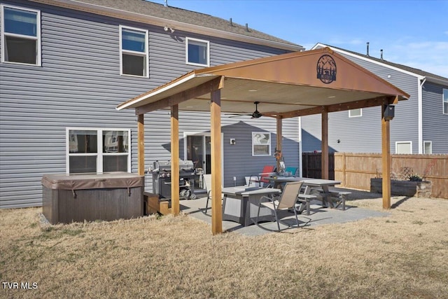 back of house featuring a hot tub, a lawn, a ceiling fan, a patio, and fence