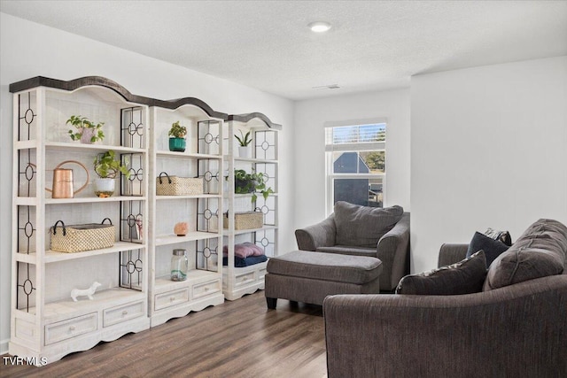 living area with a textured ceiling, visible vents, and wood finished floors