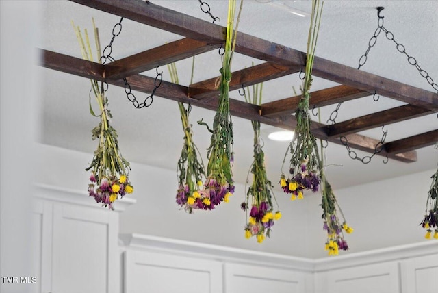 room details featuring beam ceiling, a wainscoted wall, and a decorative wall