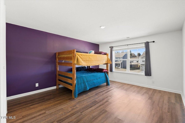 bedroom with baseboards and dark wood-type flooring