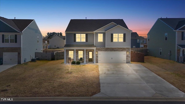 view of front of property featuring concrete driveway, an attached garage, a front yard, fence, and stone siding