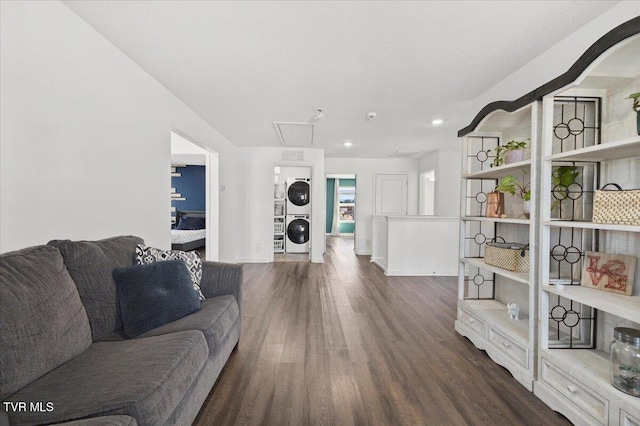 living area with stacked washer and dryer, dark wood finished floors, attic access, and baseboards