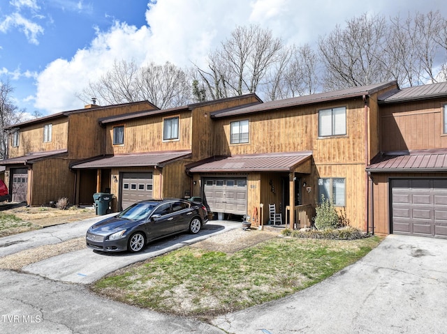 view of property featuring driveway, a standing seam roof, an attached garage, and metal roof