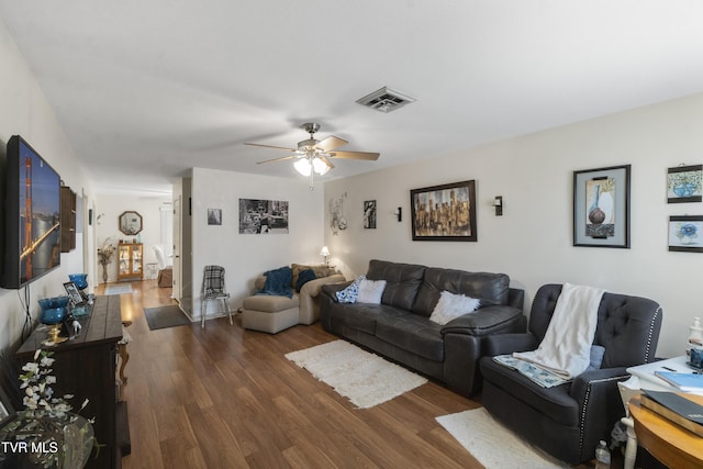 living room featuring dark wood-style floors, visible vents, and ceiling fan