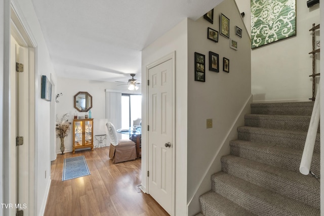 stairs featuring ceiling fan, baseboards, and wood finished floors