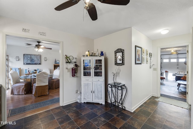 hallway with baseboards and stone tile floors