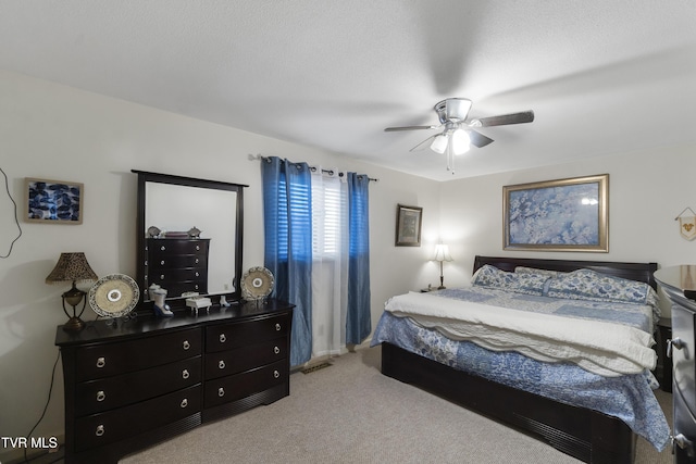 carpeted bedroom with ceiling fan and a textured ceiling