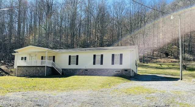 manufactured / mobile home featuring crawl space, covered porch, driveway, and a front yard