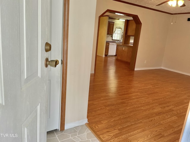 interior space with arched walkways, light wood-type flooring, baseboards, and crown molding