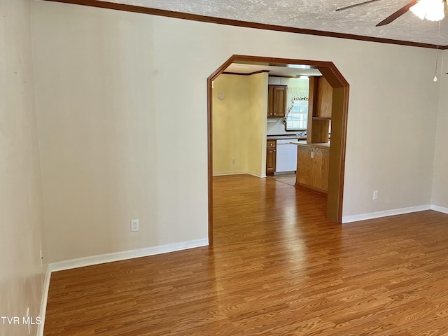 interior space featuring arched walkways, ceiling fan, a textured ceiling, wood finished floors, and crown molding