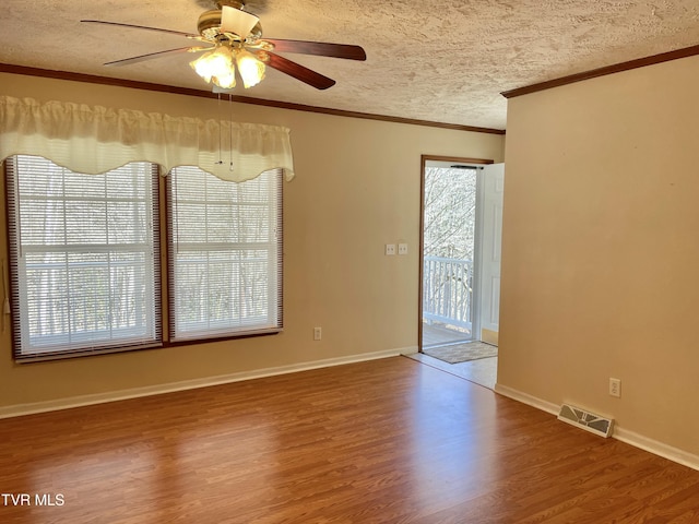 unfurnished room featuring visible vents, crown molding, a textured ceiling, and wood finished floors