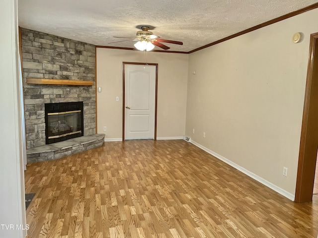 unfurnished living room with crown molding, a stone fireplace, a textured ceiling, and wood finished floors