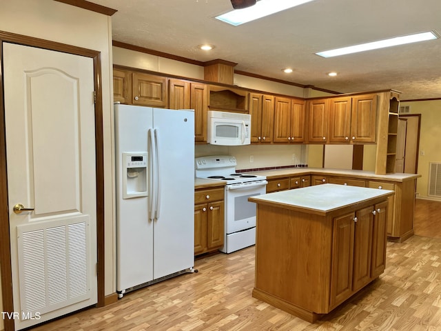 kitchen featuring white appliances, brown cabinetry, a kitchen island, and visible vents