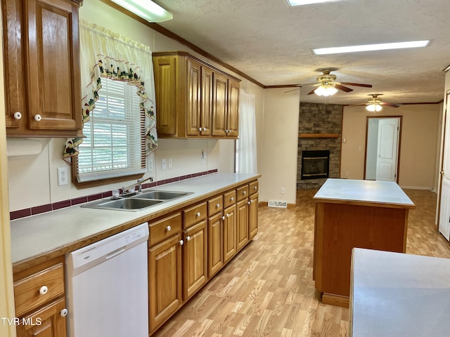 kitchen with a textured ceiling, white dishwasher, a kitchen island, and a sink