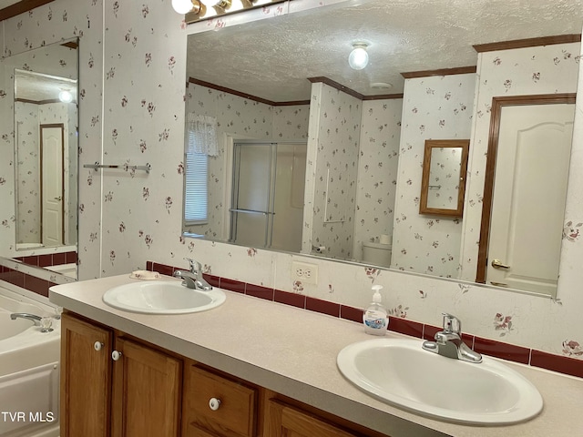 full bath featuring a sink, a textured ceiling, and wallpapered walls