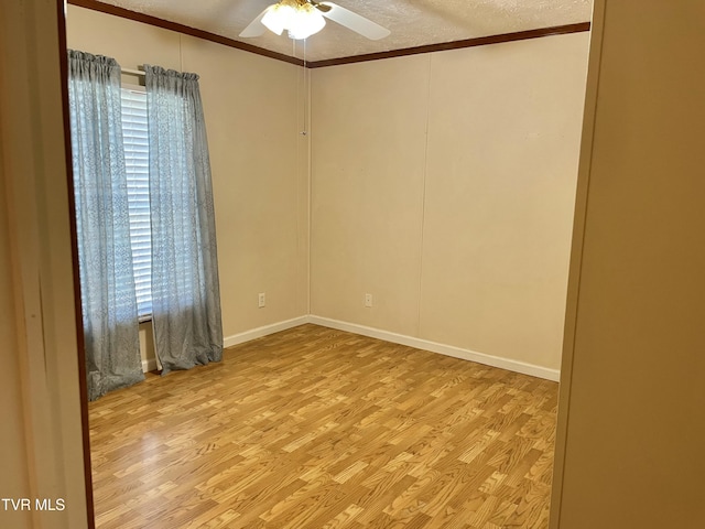 empty room featuring a ceiling fan, a healthy amount of sunlight, ornamental molding, and wood finished floors