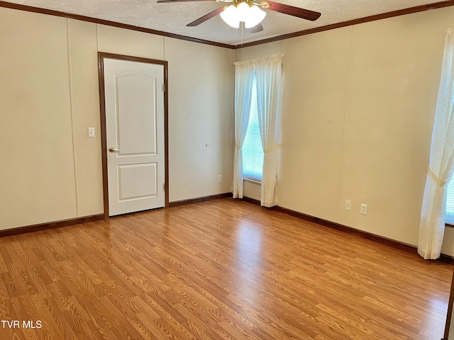 empty room with ornamental molding, light wood-style floors, ceiling fan, a textured ceiling, and baseboards