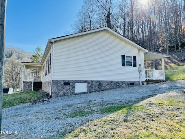 view of side of property featuring covered porch, driveway, and crawl space