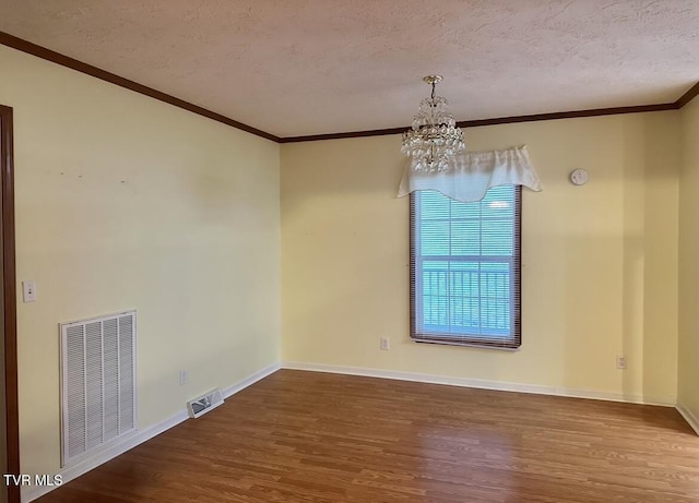 spare room featuring a chandelier, visible vents, a textured ceiling, and wood finished floors