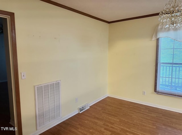 unfurnished room with visible vents, crown molding, baseboards, and wood finished floors