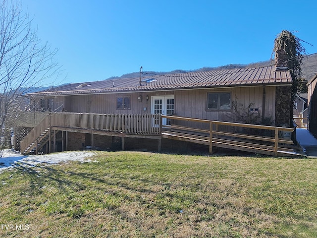 rear view of property with a lawn, stairway, metal roof, a deck, and french doors