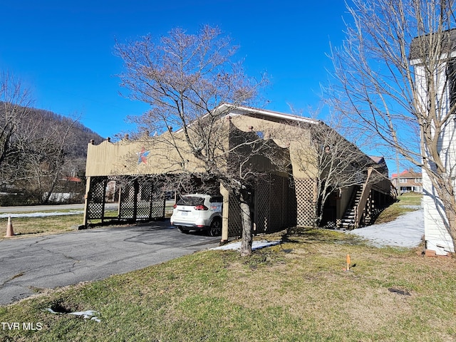 view of front of property featuring a front lawn, stairway, and aphalt driveway