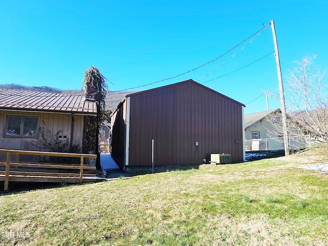 view of side of home featuring cooling unit, metal roof, a yard, and a standing seam roof