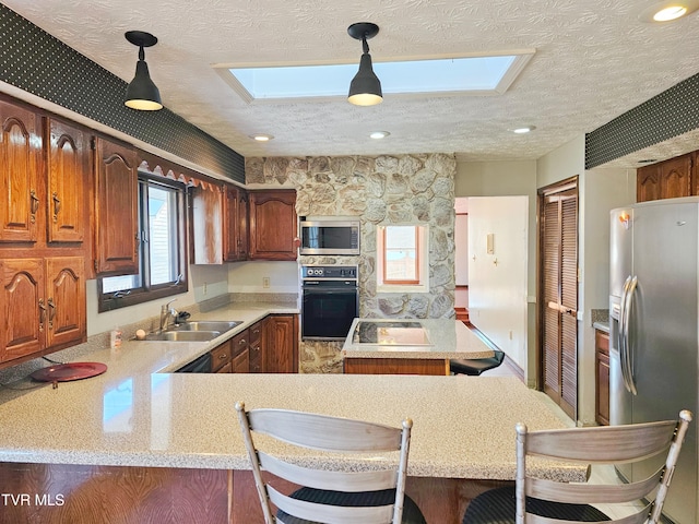 kitchen with a breakfast bar, light countertops, hanging light fixtures, appliances with stainless steel finishes, and a peninsula