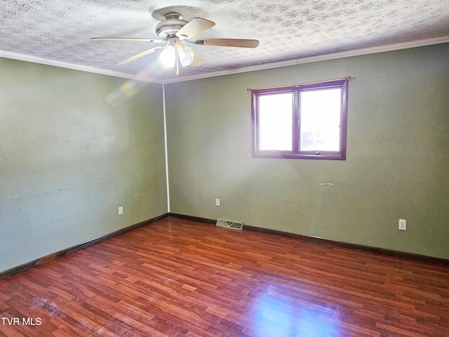 spare room with a textured ceiling, wood finished floors, visible vents, and crown molding