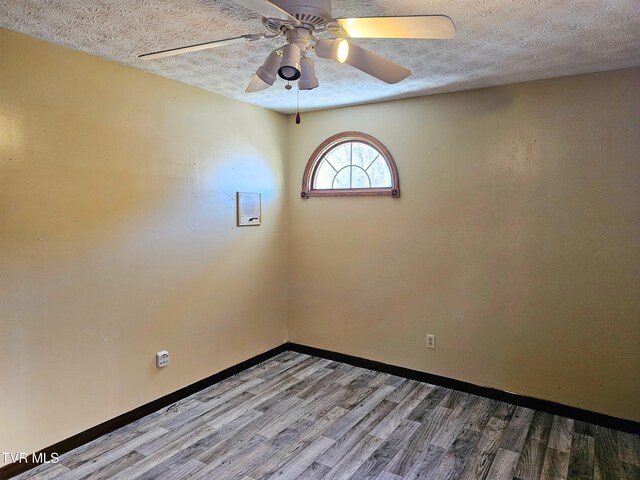 spare room featuring light wood-type flooring, ceiling fan, a textured ceiling, and baseboards