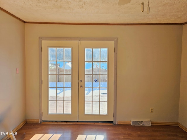 doorway with visible vents, ornamental molding, wood finished floors, and french doors