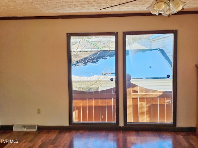 doorway featuring baseboards, visible vents, dark wood finished floors, and a textured ceiling