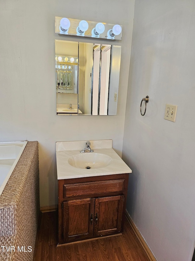 bathroom with wood finished floors, vanity, and baseboards