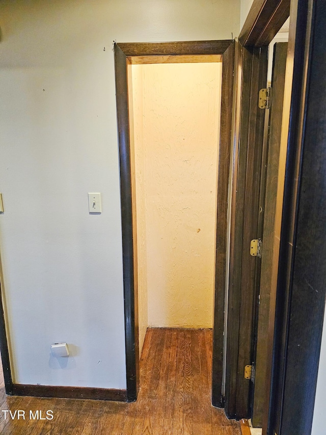 corridor with dark wood-type flooring and baseboards