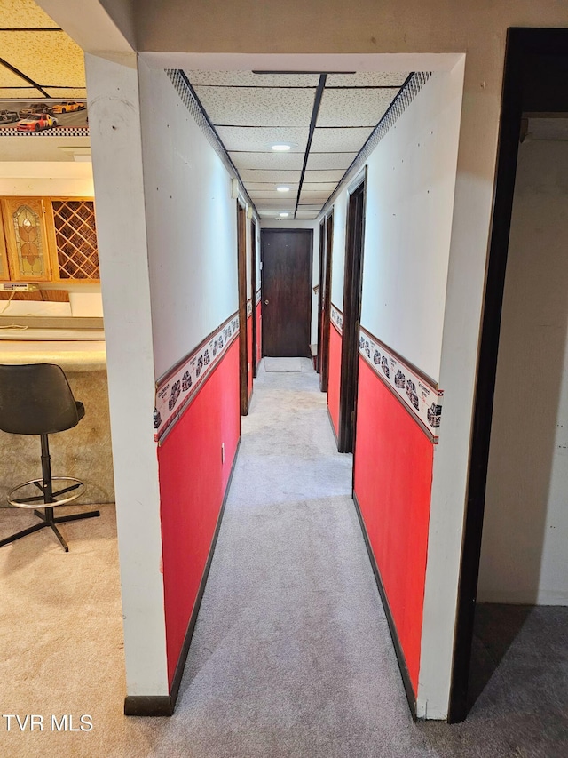 corridor featuring a paneled ceiling and carpet flooring